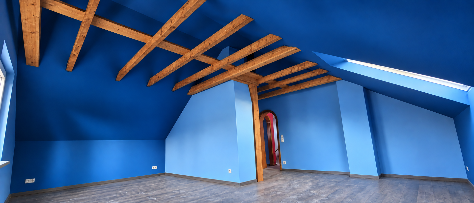 Blau gestaltetes Dachgeschoss mit sichtbaren Holzbalken